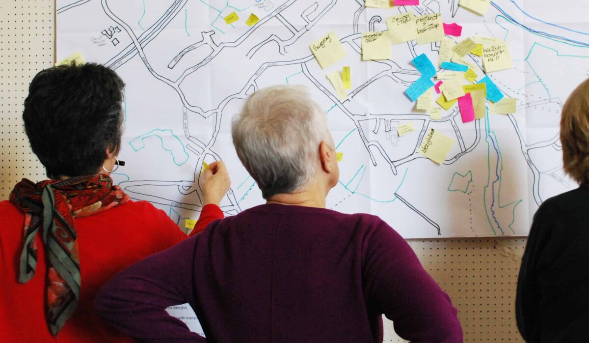 Two people viewed from behind looking at a map of their neighbourhood.