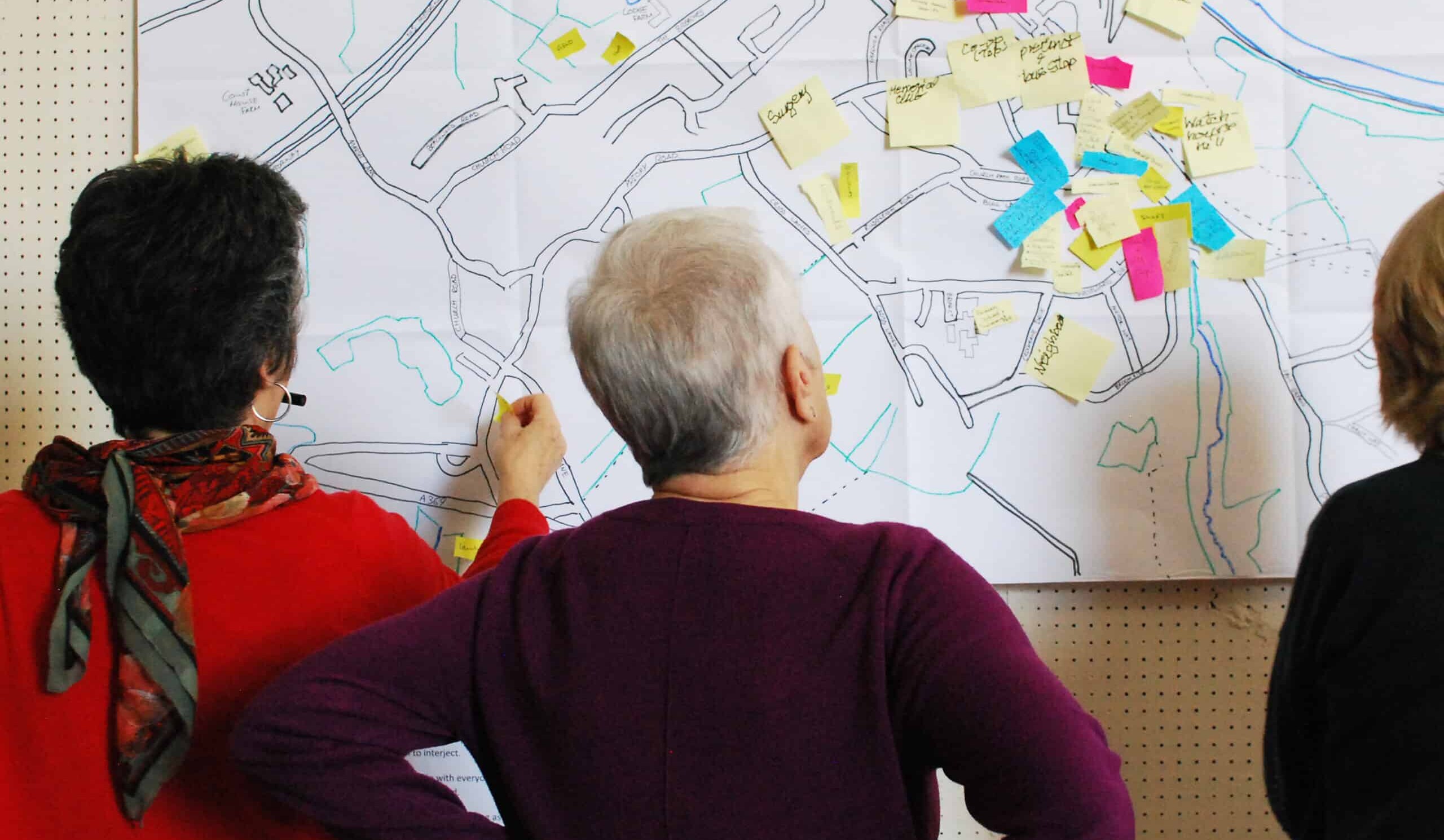 Two people viewed from behind looking at a map of their neighbourhood.