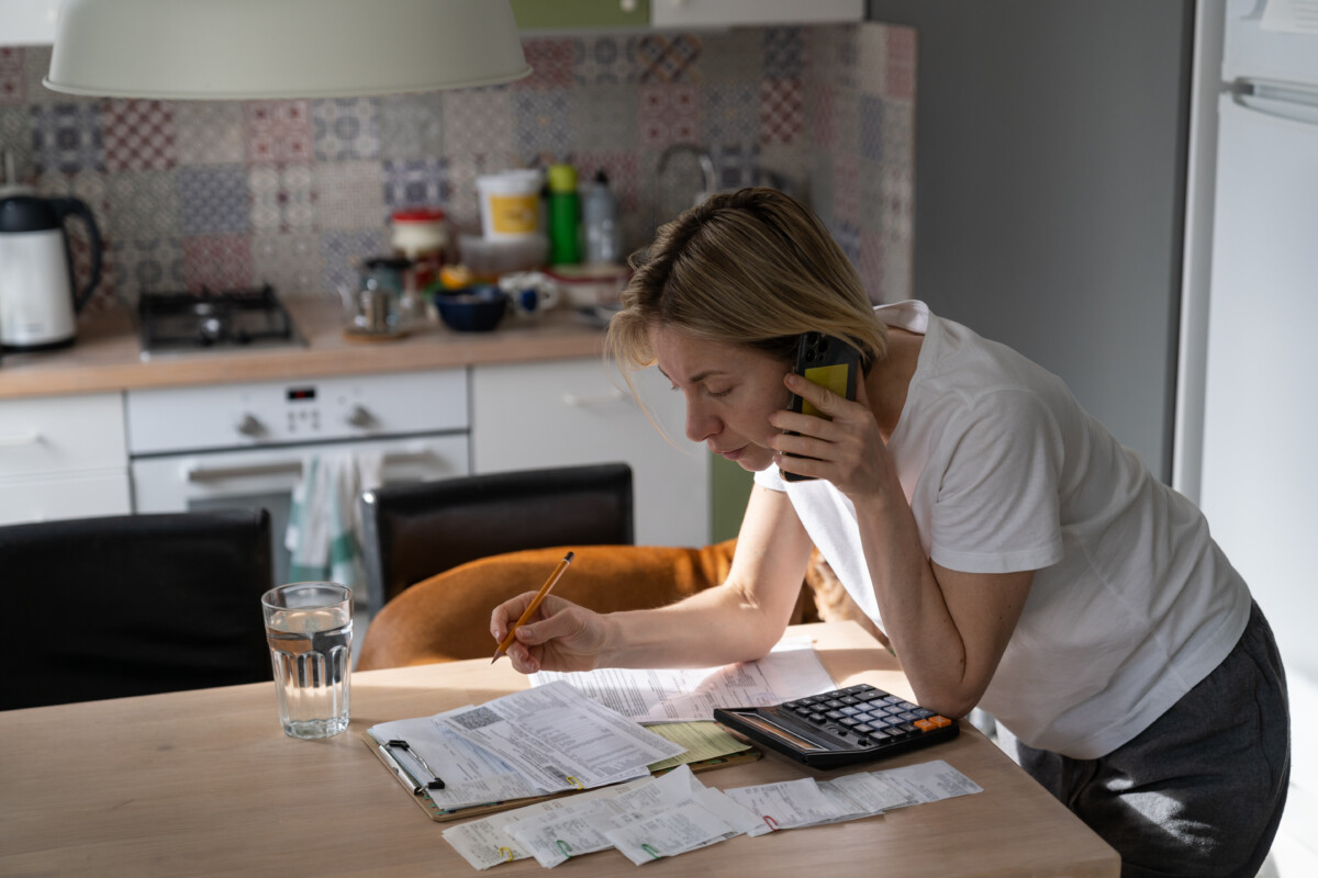Busy mature woman looks and reads unpaid bills.