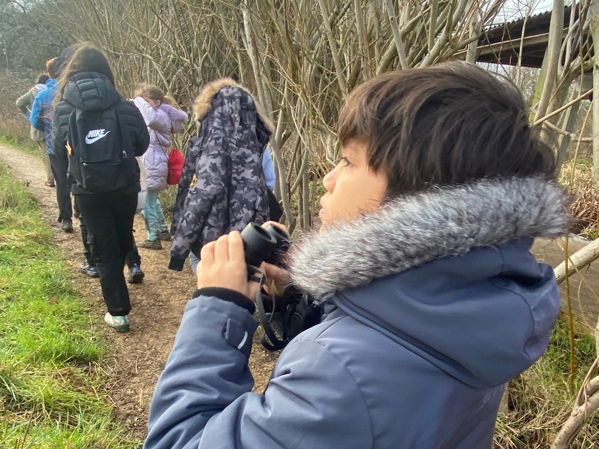 Young person in nature holding binoculars.