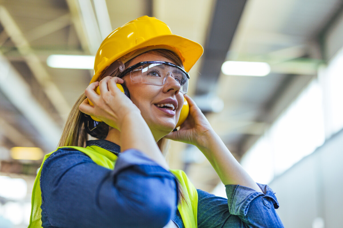 Young woman in high-vis and hard hat smiling.