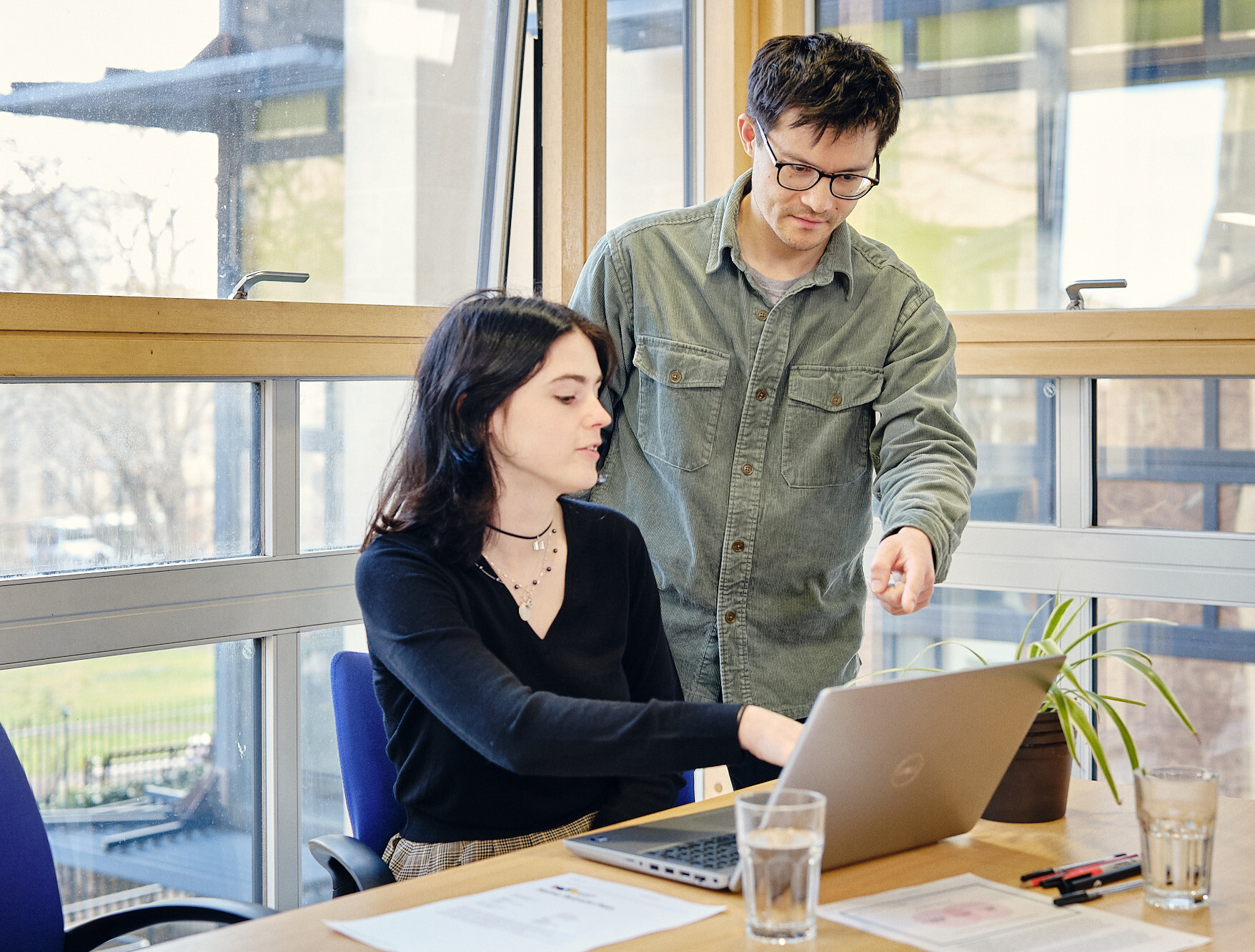 Two people gather around a laptop looking at the screen together.